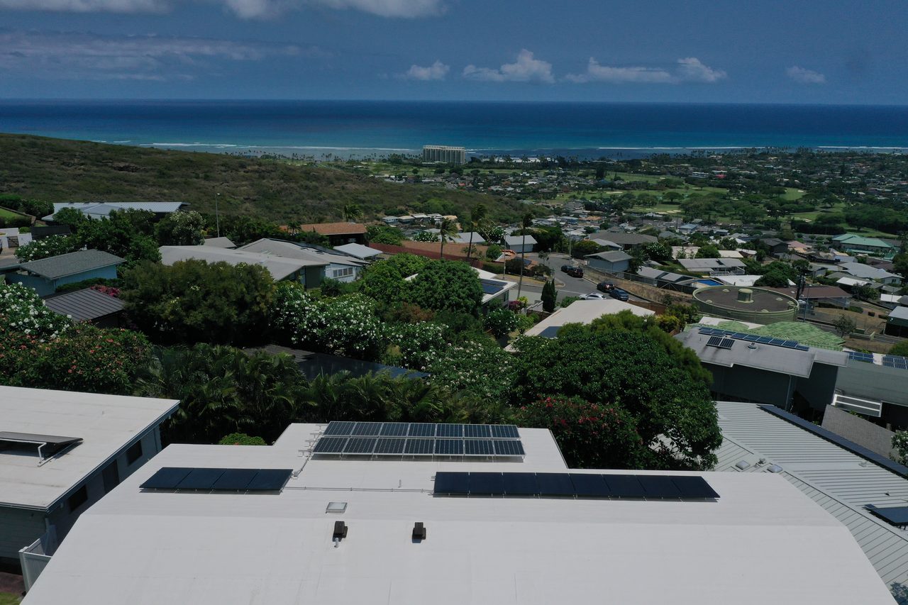 Aerial view of a rooftop solar array on an Oʻahu home above the coastline and ocean.