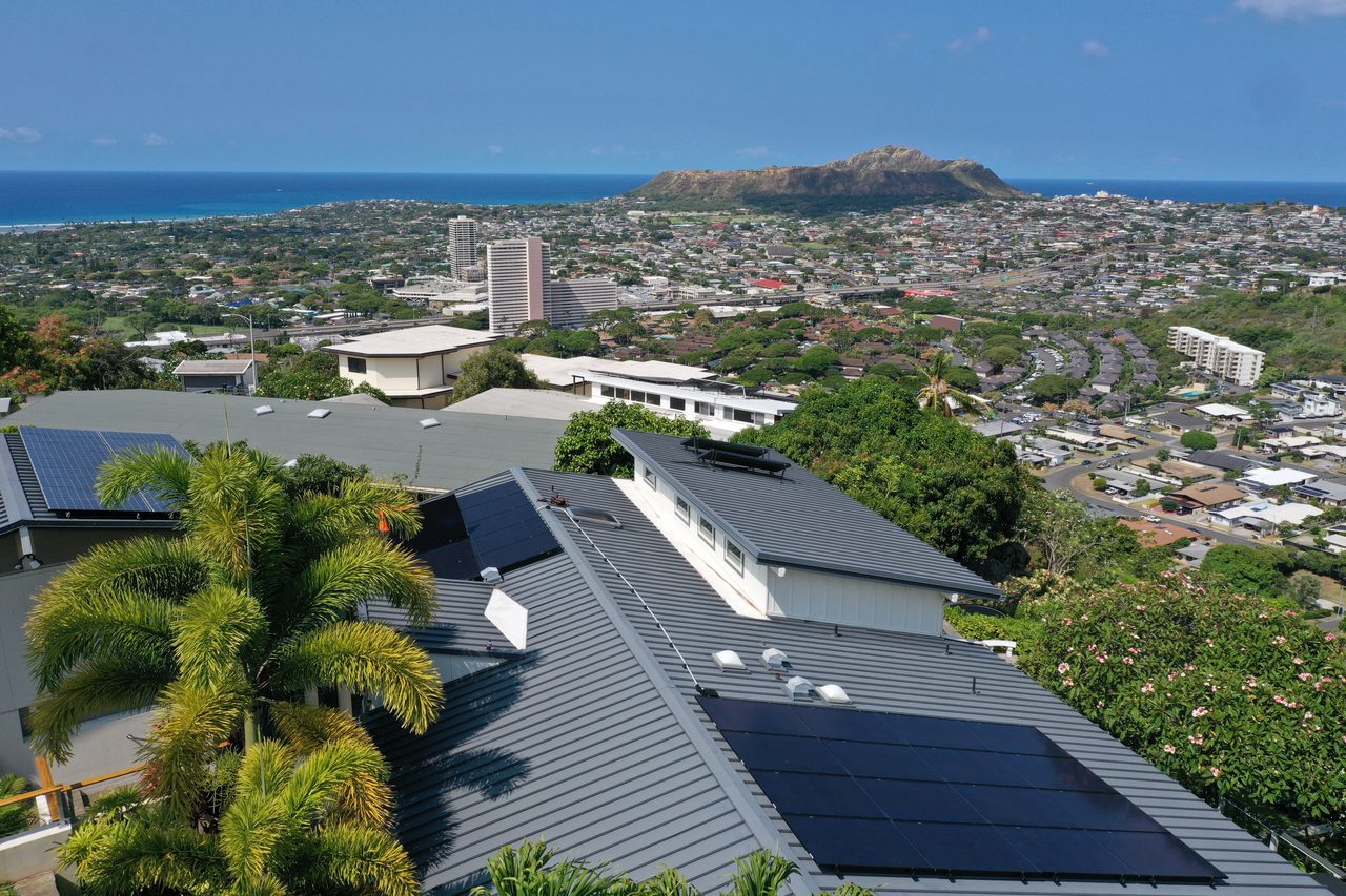 Aerial view of an Oʻahu hillside home with rooftop solar, overlooking Honolulu, Diamond Head, and the ocean.